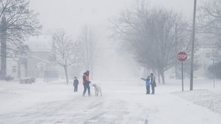 A family walks and runs through a winter snowstorm that affects much of the United States on December 23, 2022 in Flint, Michigan, USA. 